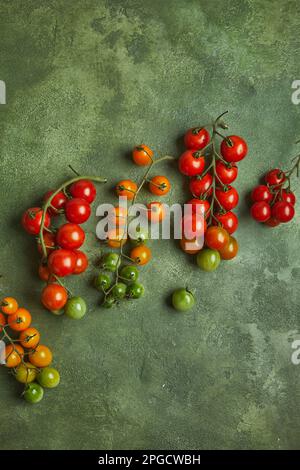 Draufsicht auf einen Haufen frisch reifer und entreifender Kirschtomaten auf grünem Hintergrund Stockfoto