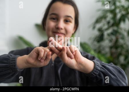 Wunderschönes, lächelndes, taubes Mädchen, das Gebärdensprache benutzt. Stockfoto