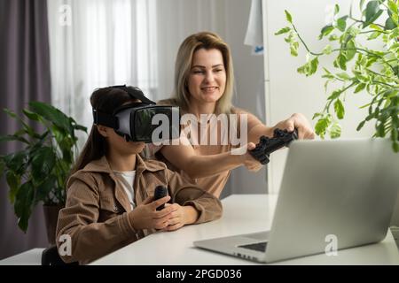 Familien und neue Technologien. Lächelnde Arbeit-zu-Hause-Mutter, die mit ihrer Tochter einen VR-Helm trägt und die virtuelle Realität erforscht. Neugieriges Teenager-Mädchen Stockfoto