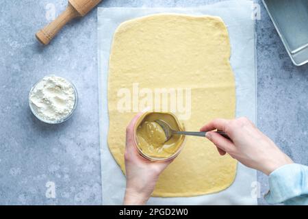 Schwenken Sie das Brot mit Pistachio Cream. Rohes Gebäck mit Zutaten auf dem Tisch. Festliches Backen Stockfoto