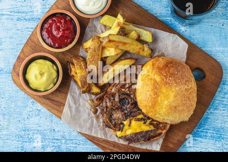 Hamburger mit karamellisierten Zwiebeln, mit Saucen und pommes frites Stockfoto