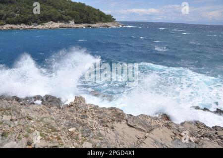 Die Meereswelle stürzt auf den Felsen und lässt das spritzwassernde Wasser und den weißen Luftschaum blasen. Stockfoto