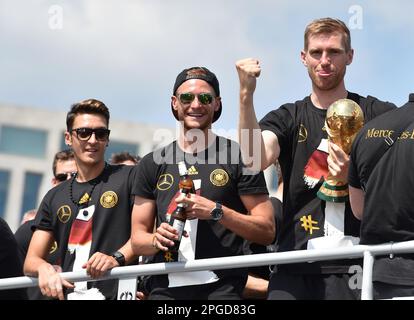 EINGEREICHT - 15. Juli 2014, Berlin: Die Nationalmannschaftsspieler Mesut Özil, Benedikt Höwedes und per Mertesacker (l-r) stehen beim Empfang der Nationalmannschaft in der Hauptstadt im offenen Team-Bus jubelnd mit der Trophäe der Weltmeisterschaft an. Nach 1954, 1974 und 1990 ist Deutschland zum vierten Mal Weltmeister geworden, mit einem Sieg über Argentinien. Der ehemalige Weltmeister Özil beendete seine Karriere als Profi-Fußballer mit 34 Jahren. Der 92-fache Deutsche Internationale gab am Mittwoch auf seinen verifizierten Profilen auf Twitter, Instagram und Facebook seinen sofortigen Ruhestand bekannt. Foto: Jens Kalaene/dpa-Zen Stockfoto