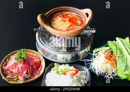 Koreanischer würziger Hot Pot mit Rindfleisch und Nudeln auf schwarzem Hintergrund Stockfoto