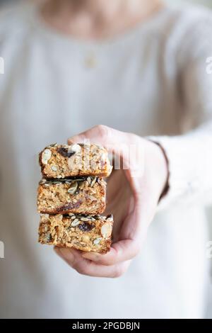 Eine Frau mit drei Portionen selbstgemachtem Flapjack. Der Flapjack wurde mit verschiedenen Früchten und Nüssen gebacken, darunter Datteln, Sultaninen und Walnüsse Stockfoto