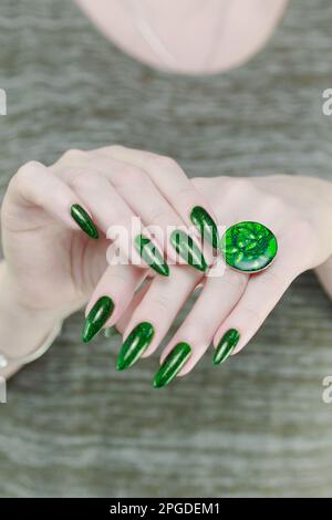 Frauenhand mit langen Nägeln und grünem Nagellack Stockfoto
