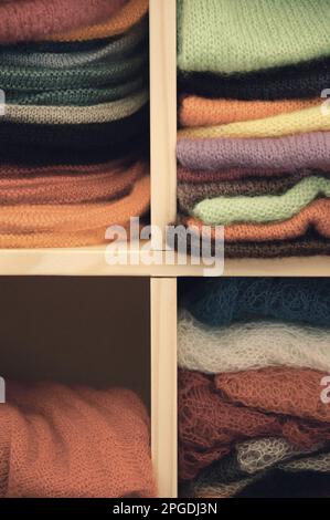 Ein Stapel bunter Strickkleidung - Pullover, Kleider, Strickjacken usw. Getöntes Foto. Stockfoto