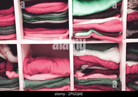 Ein Stapel bunter Strickkleidung - Pullover, Kleider, Strickjacken usw. Getöntes Foto. Stockfoto