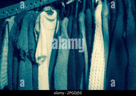 Ein Stapel bunter Strickkleidung - Pullover, Kleider, Strickjacken usw. Farbiges Schwarzweißfoto. Stockfoto