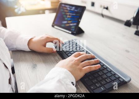 Nahaufnahme eines unbekannten Mannes, Programmiergerät, der auf einer Tastatur tippt Stockfoto