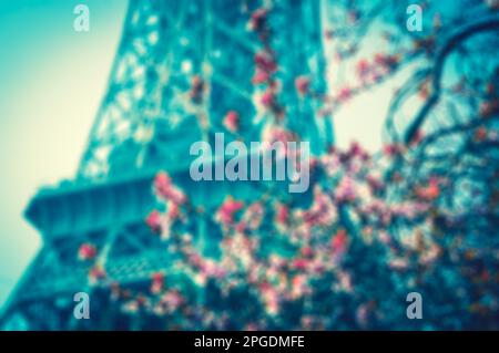 Frühling in Paris. Blühender Kirschbaum und Eiffelturm im Hintergrund. Verschwommenes Bild mit Tonwertkorrektur. Stockfoto