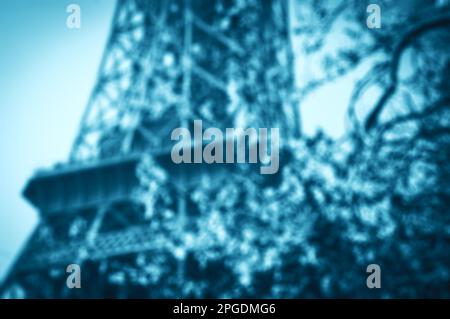 Frühling in Paris. Blühender Kirschbaum und Eiffelturm im Hintergrund. Blau getöntes, verschwommenes Schwarzweißbild. Stockfoto