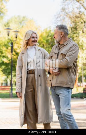 Lächelndes, reifes Paar, das im Frühlingspark spaziert, Stockbild Stockfoto
