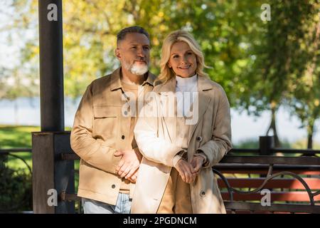 Lächelndes, reifes Paar, das in der Nähe der Brücke im Spring Park steht, Stockbild Stockfoto