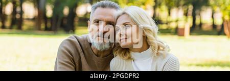 Porträt eines charmanten Paares mittleren Alters, das im Frühling zusammen im Green Park sitzt, Banner, Stock Image Stockfoto