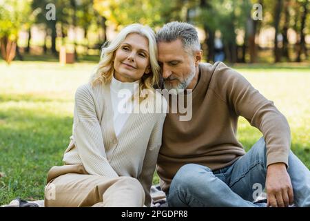 Porträt eines charmanten Paares mittleren Alters, das im Frühling im Green Park sitzt, Stockbild Stockfoto