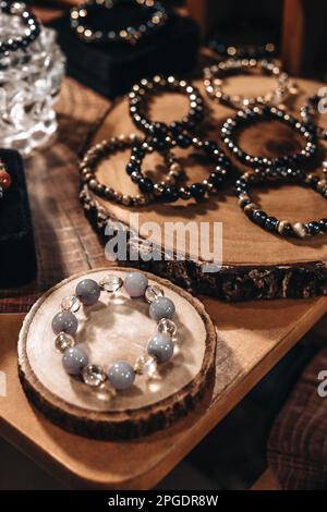 Armbänder mit Steinperlen auf einem Ständer aus natürlichem Holz Stockfoto