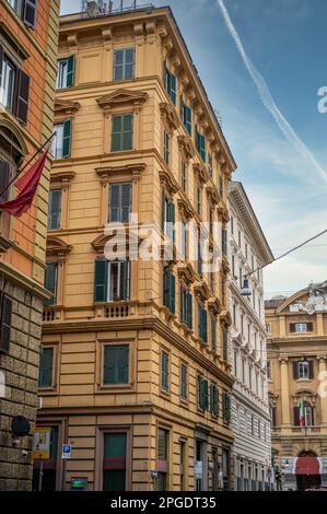 Blick aus der Vogelperspektive auf ein Stadtbild mit einem alten gelben Gebäude mit mehreren offenen Fenstern vor dem Hintergrund anderer städtischer Strukturen Stockfoto