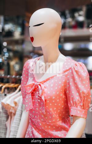 Weibliche Schaufensterpuppe mit roten Lippen in einem pinken Sommerkleid mit Herzen. Frühlingssommer-Modekollektion im Einkaufszentrum Stockfoto