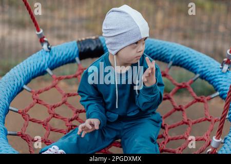 Süßer kleiner Junge mit Down-Syndrom mit seiner Mutter, schaukelt auf einer Schaukel, Seifenblasen Stockfoto