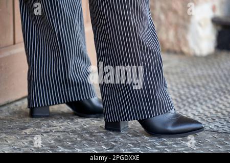 Frauenbeine in ausgezogenen Hosen und geschlossenen schwarzen Schuhen Stockfoto