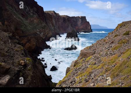 Eine malerische Aussicht auf eine zerklüftete Küste mit mächtigen Wellen, die gegen die zerklüfteten Felsen darunter schlagen Stockfoto