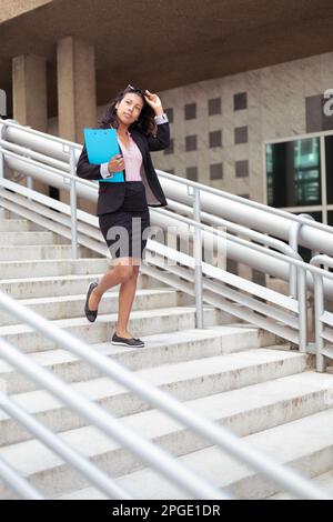 Elegante junge Erwachsene Latina-Frau, die auf der Straße läuft. Unternehmerische Person, Geschäftsfrau. Stockfoto