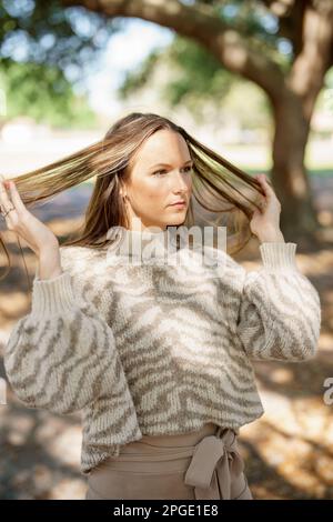 Attraktive junge Frau, die sich in den Herbsttrends des Parks posiert Stockfoto