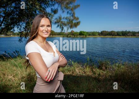 Schöne junge Frau, die draußen posiert, mit verschränkten Armen Stockfoto