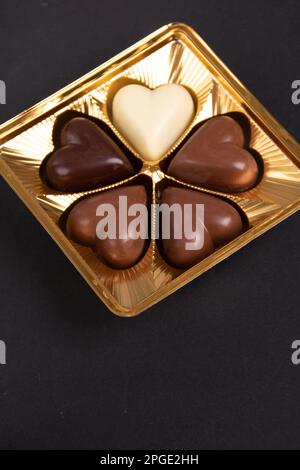 Fotoweiß, schwarz, Milchschokolade in einer Verpackung auf schwarzem Hintergrund Stockfoto