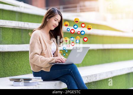 Eine junge Studentin hat Spaß beim Spielen sozialer Medien auf ihrem Laptop. Stockfoto