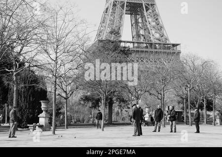 PARIS, FRANKREICH - 12. MÄRZ 2016: Eine Gruppe älterer Männer, die im Park am Fuße des Eiffelturms Petanque spielen. Schwarzweißes historisches Foto Stockfoto