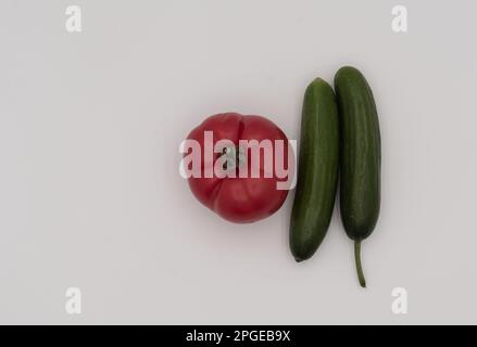 Draufsicht von zwei Gurkenstücken und einer Tomate isoliert auf weißem Hintergrund. Stockfoto