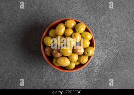 Schale voll mit grünen Oliven auf schwarzem Hintergrund Stockfoto