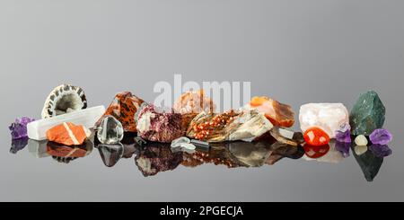 Breites Banner mit einer Gruppe bunter Steine und Mineralien, die in einer Reihe auf der reflektierenden Oberfläche angeordnet sind. Das Crystal Collector -Display Stockfoto