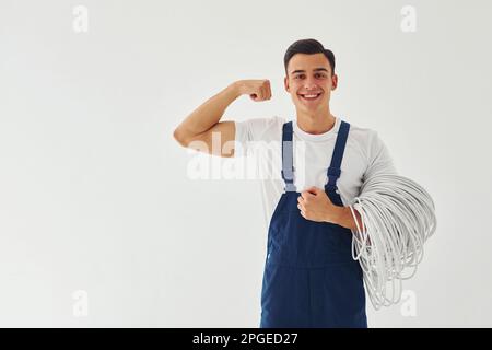 Männlicher Arbeiter in blauer Uniform, der im Studio vor weißem Hintergrund steht Stockfoto