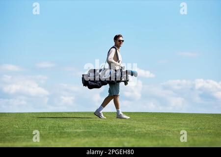 Minimales seitliches Porträt eines reichen, sportlichen Mannes mit Golftasche, der auf dem grünen Feld gegen den Himmel läuft, Kopierraum Stockfoto