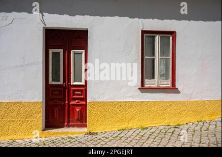 Ein traditionell bemaltetes Haus mit Fenster und Tür in der Agarve Portugal, gelb und rot mit roter Fußleiste gestrichen. Stockfoto