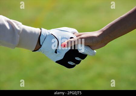 Nahaufnahme von zwei Sportlern, die nach dem Spiel im Freien vor grünem Gras die Hand schütteln Stockfoto