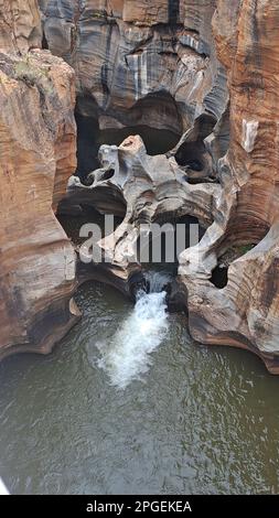 Eine malerische Szene eines sanft fließenden Flusses, der über felsiges Gelände stürzt und einen kleinen Wasserfall schafft Stockfoto