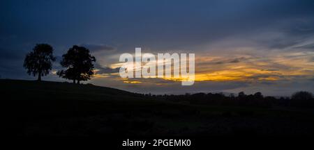 Panoramaaussicht in der Dämmerung mit Sonnenuntergang und Silhouetten an den Hügeln Großbritanniens. Stockfoto