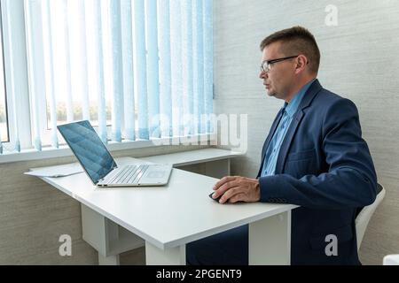 Porträt eines seriös eleganten, gut aussehenden Geschäftsmannes und professionellen Geschäftsführerin. Hübscher reifer kaukasischer Mann in Anzug in der Nähe des Schreibtisches in Mo Stockfoto