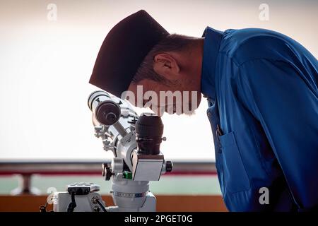 Ein Beamter des Islamischen Religionsrats von Selangor führt „rukyah“ durch, eine Mondsichterungszeremonie, um den Beginn des heiligen Monats Ramadan in Bukit Malawati zu bestimmen. Stockfoto