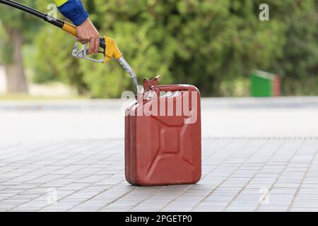 Ein Mann füllt kanister an einer Tankstelle. Ein Mann füllt an einer Tankstelle Benzin in einen Kanister. Ich gieße Benzin in einen Kanister. Stockfoto