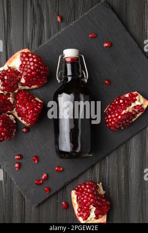 Granatapfel, verstreute Granatapfelsamen und Granatapfelsaft auf einem dunklen Holzhintergrund von oben. Frisch gepresster Granatapfelsaft Stockfoto