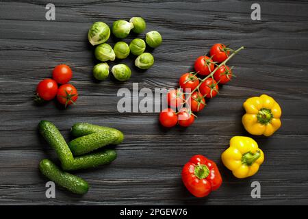 Frische Gurken, Kirschtomaten, bunte Paprika, rosenkohl auf dunklem Holzhintergrund mit Blick von oben. Rohes Gemüse. Richtige Ernährung. Stockfoto