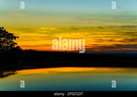 Dämmerung im Rheintal mit Bäumen, Wiesen und Feldern. Sommerliche Abendstimmung mit farbigem Himmel. Stockfoto