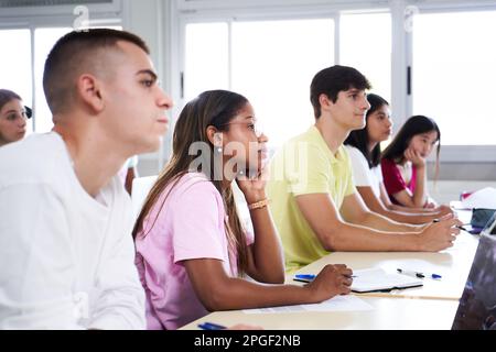Afroamerikanische Studentin, die eine Vorlesung hört, während sie einen Kurs im Klassenzimmer besucht. Multiethnische Gruppe junger High-School-Colleges Stockfoto