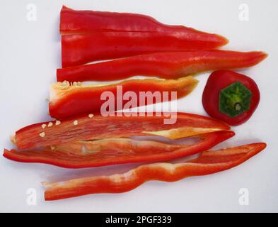 Rotes süßes Capsicum annuum in Scheiben auf einem weißen Schneidebrett. Stockfoto