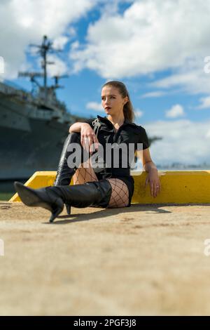 Fit Young Woman in Black Romper am Pier vor dem USS Aircraft Carrier | USS Hornet Stockfoto